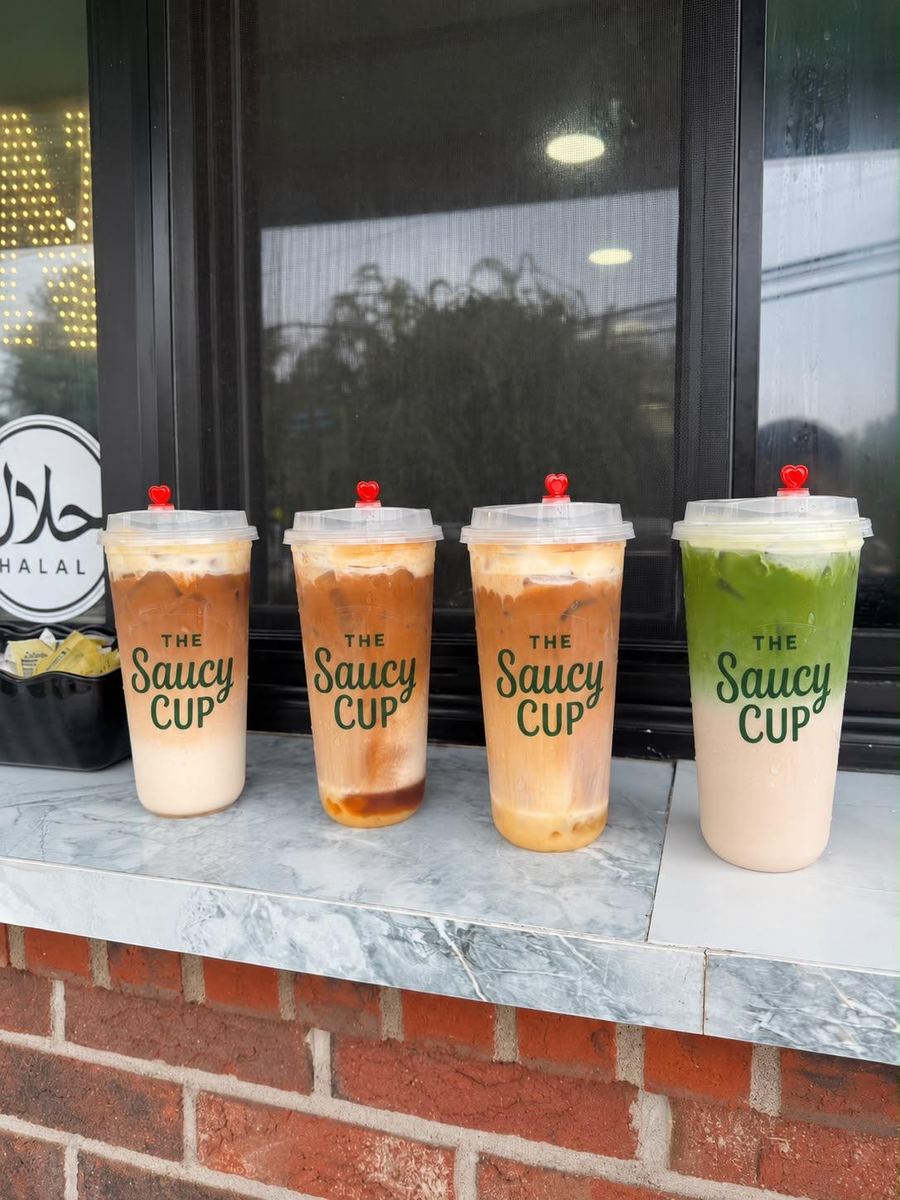 Four Saucy Cup iced drinks lined up by the window, halal sign in view
