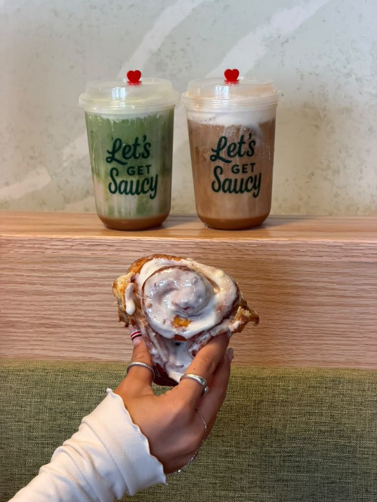 Matcha and latte Let's Get Saucy cups with a cinnamon roll